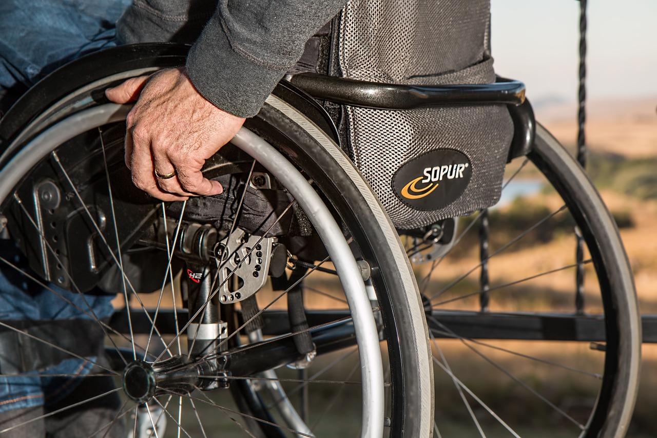 picture of an old man with a wheelchair wheeling his way towards prescription assistance programs