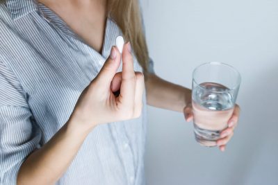 Woman Holding Pill and Glass of Water